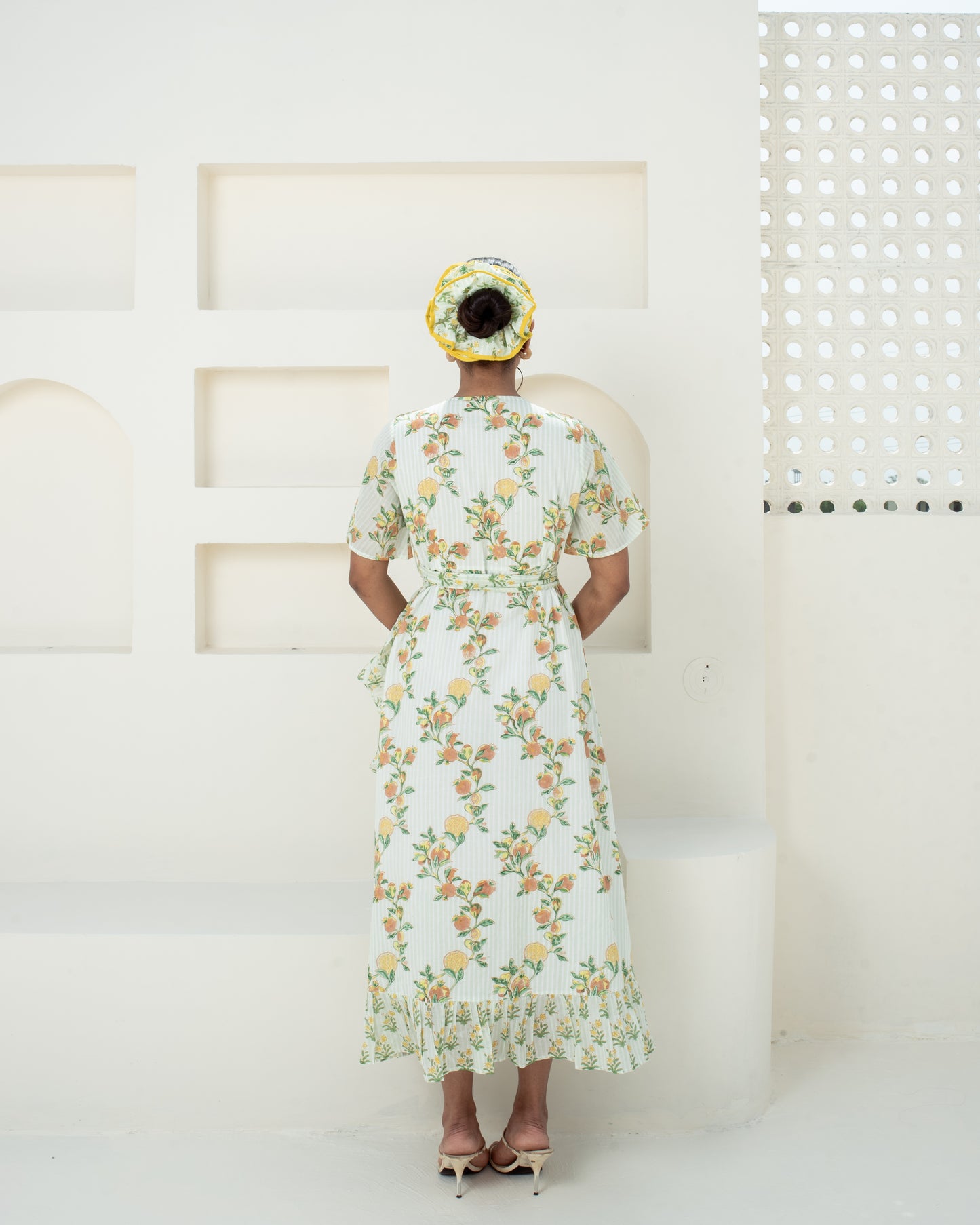 Model wearing the Anar Bagh yellow floral hand block printed cotton wrap dress back details with tie waist
