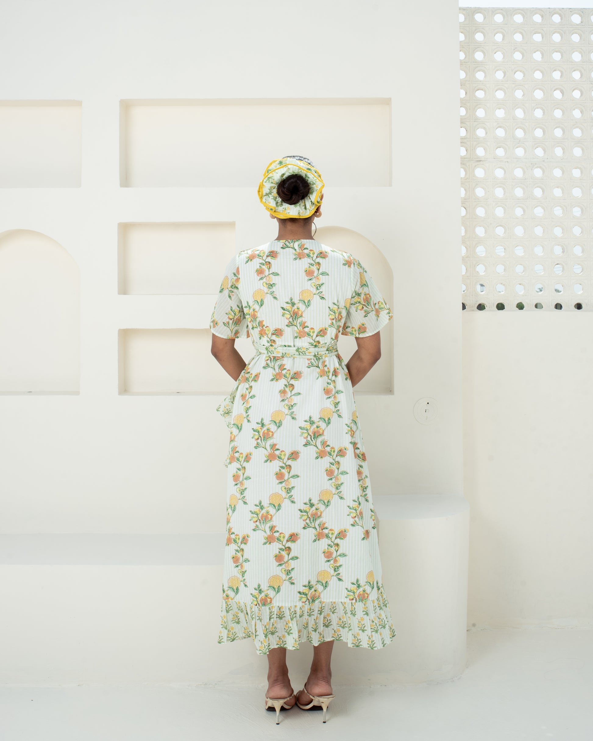 Model wearing the Anar Bagh yellow floral hand block printed cotton wrap dress back details with tie waist